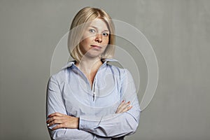 Young smiling woman in a blue shirt and trousers. Business success. Gray background