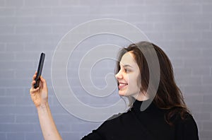 Young smiling woman through the camera looks at her appearance