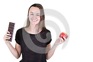 Young smiling woman with chocolat and an apple having doubts