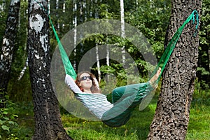 Young smiling woman in dark sunglasses lies in hammock