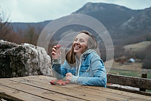 Young smiling woman eating strawberries in the nature on a background of mountains