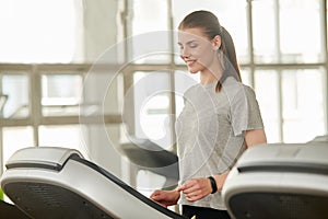 Young smiling woman exercising on treadmill.