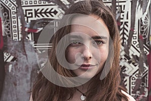 Young smiling woman in front of a wall with torn posters