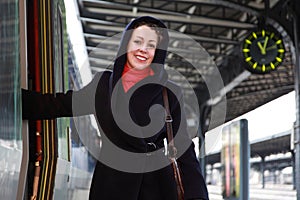 Young smiling woman going to enter a train.