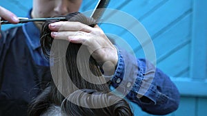 Young smiling woman hairdresser cutting hair of cute hipster man in experimental outdoor barbershop on summer festival