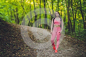 Young smiling woman hiker hiking mountain trail, walking on grassy hill, wearing backpack. Outdoor activity, tourism