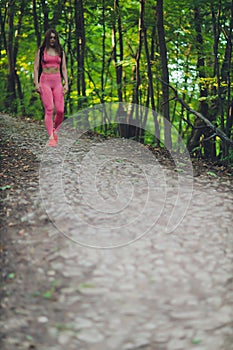 Young smiling woman hiker hiking mountain trail, walking on grassy hill, wearing backpack. Outdoor activity, tourism