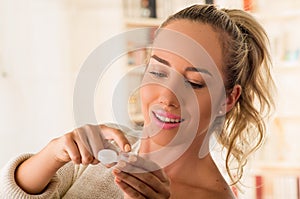 Young smiling woman holding contact lenses cases and lens