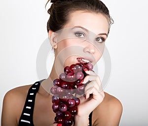 Young smiling woman holding fresh red bunch of grapes.