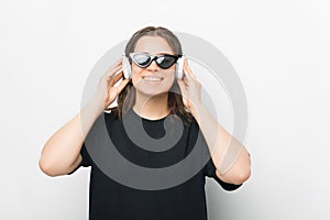 Young smiling woman is holding her headphones and listening to the music, audio book or meditations.