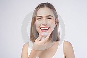 Young smiling woman holding invisalign braces over white background studio, dental healthcare and Orthodontic concept photo