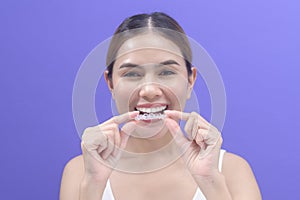 Young smiling woman holding invisalign braces in studio, dental healthcare and Orthodontic concept photo