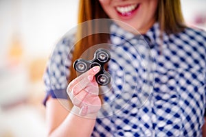 Young smiling woman holding a popular fidget spinner toy in her hand