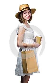 Young smiling woman holding a shopping bag and a paper cup