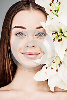 Young smiling woman holding white lily flower, beautiful face closeup