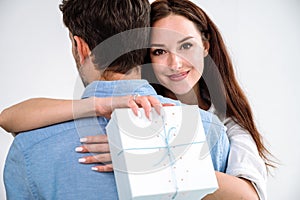 Young smiling woman hugging man and holding present in box