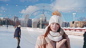 Young smiling woman ice skating outside on ice rink central city square at Christmas holiday, active winter leisure in