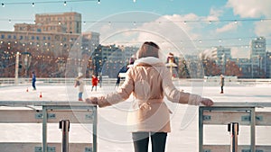 Young smiling woman ice skating outside on ice rink central city square at Christmas holiday, active winter leisure in