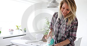 Young Smiling Woman Ironing Clothes On Ironing Board