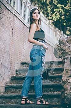 Young smiling woman with jeans and handbag. Outdoors. Long hair and big eyes