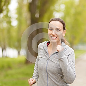 Young smiling woman jogging in park in the morning