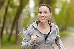 Young smiling woman jogging in park in the morning