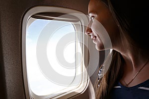 Young smiling woman looking through the plane window