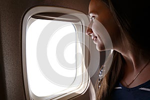 Young smiling woman looking through the plane window with white space