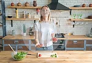 Young smiling woman making salad in the kitchen. Throwing up tomatoes and smiling. Having fun. Healthy food. vegetable salad. Diet