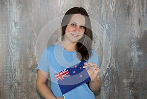 A young smiling woman with a new Zealand flag in her hand.