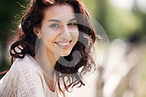 Young smiling woman outdoors portrait. Soft sunny colors.