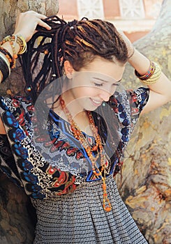 Young smiling woman portrait with dreadlocks dressed in boho style ornamental dress