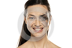 A young smiling woman posing with half face dirty and half cleansed of makeup on a white background photo