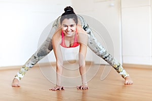 Young smiling woman practicing yoga, Ardha Padmasana pose, mudra, working out
