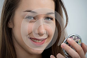 Young and smiling woman putting lipstick