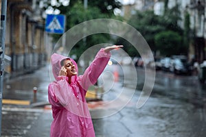 Young smiling woman with raincoat while enjoying a rainy day.