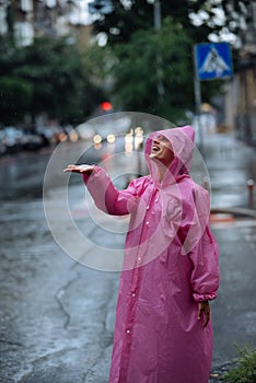 Young smiling woman with raincoat while enjoying a rainy day.