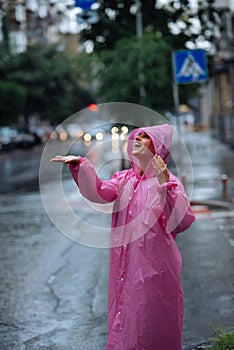 Young smiling woman with raincoat while enjoying a rainy day.
