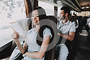 Young Smiling Woman Reading Book in Tourist Bus