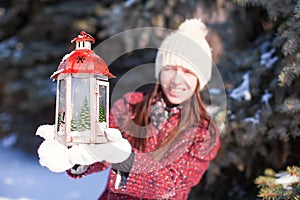 Young smiling woman with red Christmas lantern in winter forest