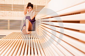 Young smiling woman relaxing in a wooden sauna