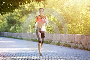 Young smiling woman running in park in the morning