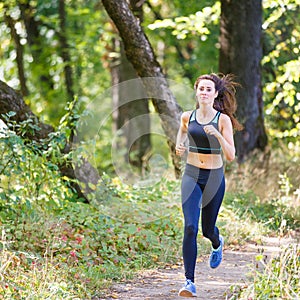 Young smiling woman running in park in the morning