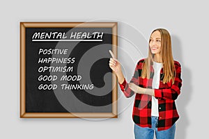 Young smiling woman shows you on board with words: Mental healthy, Positive, Happiness, Optimism, Good Mood, Good Thinking.