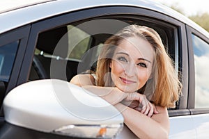 Young smiling woman sitting in car taking key