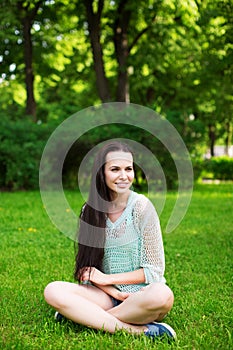 Young smiling woman sitting on grass.