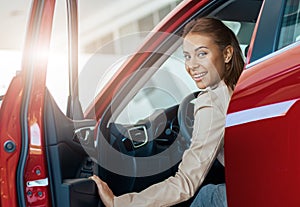 Young smiling woman sitting inside her new car. Concept for car rental