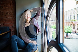 Young woman sitting on window sill in cafe