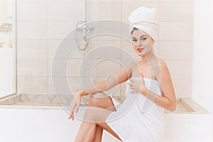 A young smiling woman takes care of her skin and hair after a shower. Spa treatments at home, skin care.