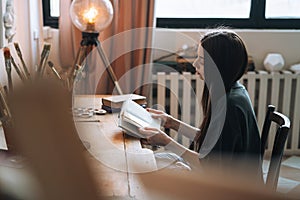 Young smiling woman teenager girl student with dark long hair in casual reading book at home